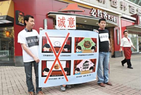 图为:2013年6月5日，崇文门必胜客餐厅门口，两名盲人举牌抗议必胜客在广告中使用对盲人歧视性用语。
