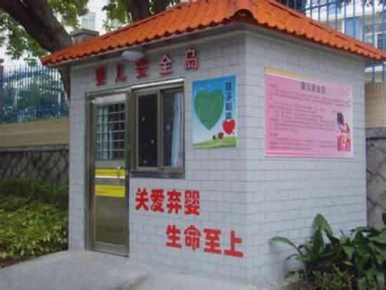 图为：广州首个婴儿安全岛，墙上写着两行红色的大字：关爱弃婴，生命至上。