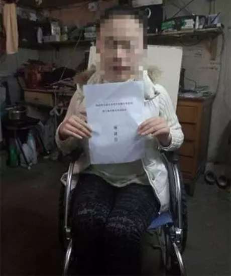 图为：脑性麻痹女孩田晴（化名）坐在轮椅上，展示写给上海市教育考试院的感谢信。