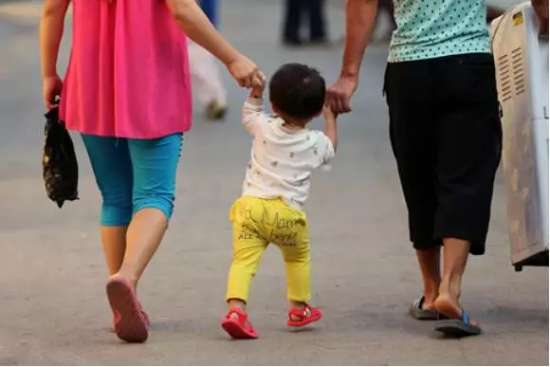 图为：爸爸妈妈和小朋友手拉手在路上行走。