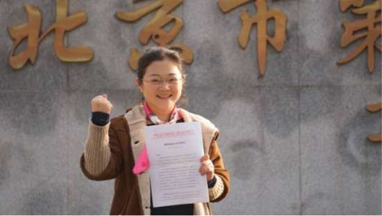 6.袖珍人诉国家工商总局政府信息公开案.jfif.jpg 图为:袁纳纳手持政府信息公开告知书,做出“加油”的手势。