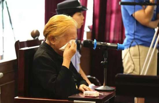 图为：庭审现场的被告席上，杀害46岁智力障碍儿子的黄老太
