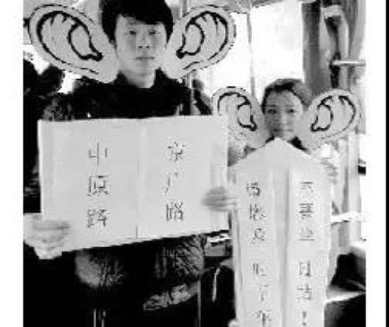 1.82路公交车上,李阳和同伴在表演行为艺术.jpg 图为:82路公交车上,李阳和同伴在表演行为艺术。三位听障伙伴戴着放大版的耳朵模型,每到一站,李阳都会站在司机的背后,举起该站点的名称,同伴则举着:“请您及时下车,不要坐过站!”的纸牌。